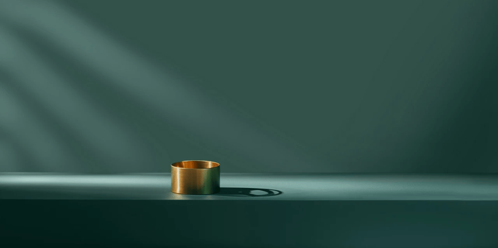 A simple brass ring placed on a muted green surface, casting a shadow.